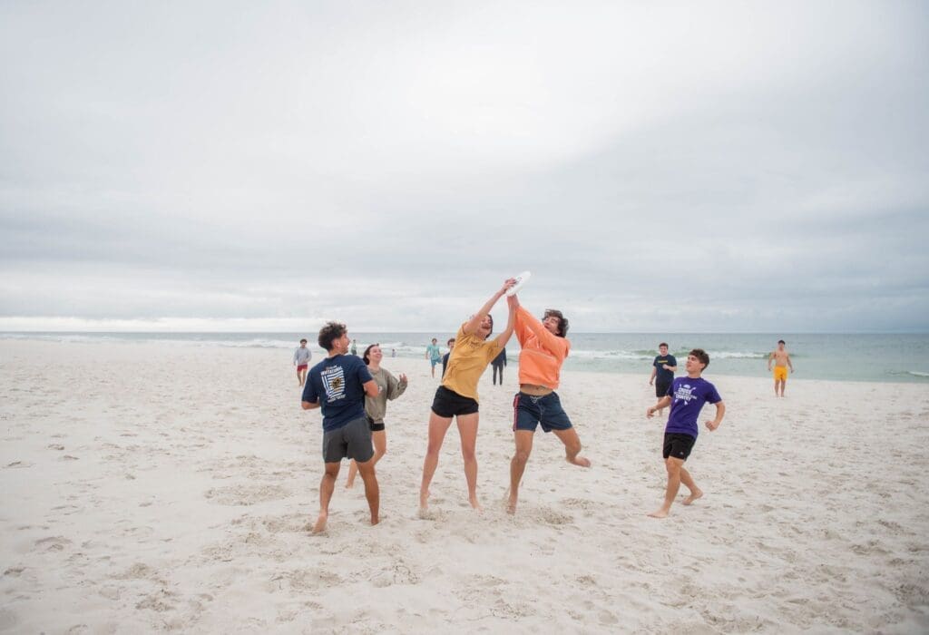Group of students play a game outdoors on the beach