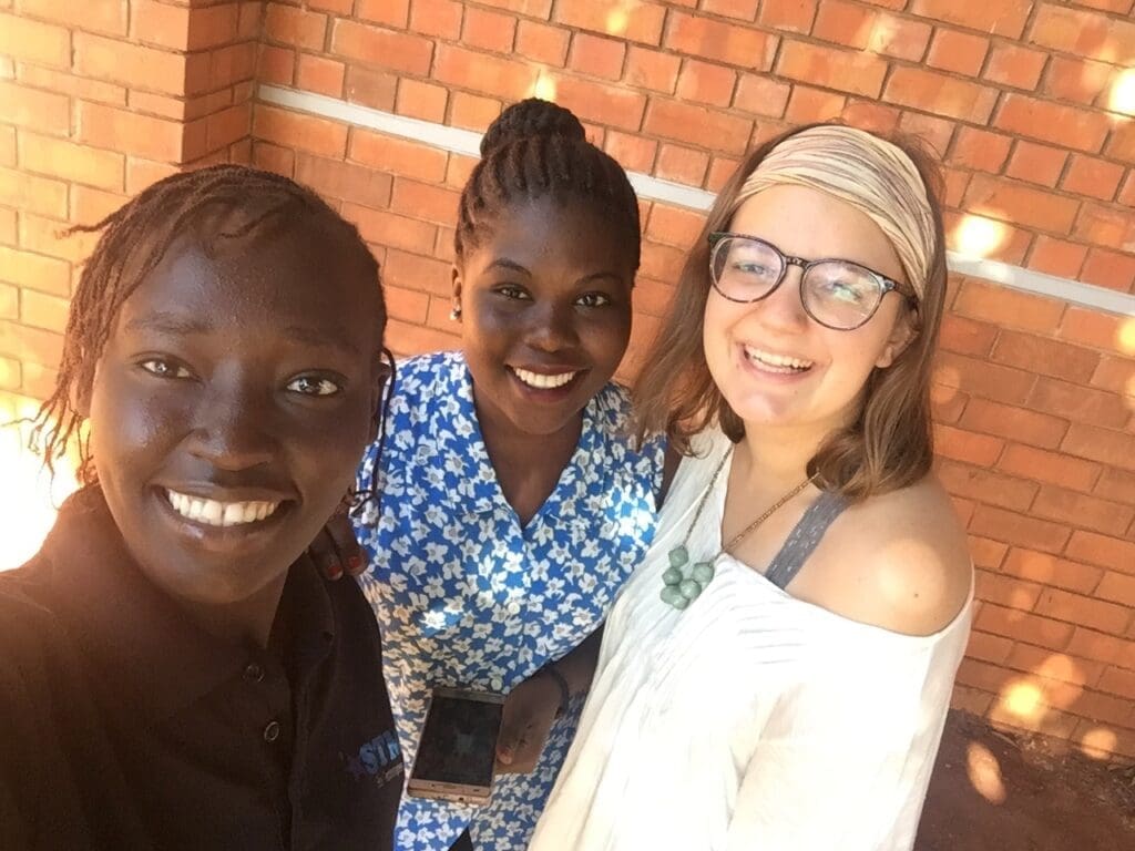 Asbury female student poses with two Ugandan women on a school trip