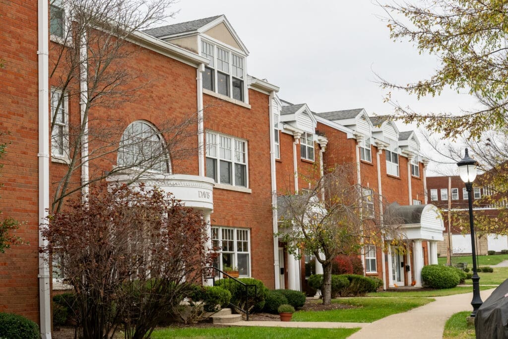 Side exterior view with trees blocking full view of Aldersgate Commons on the campus of Asbury University.