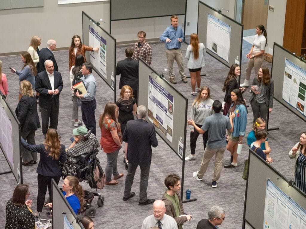 Group photo of SEARCH Symposium presenters in front of their work talking with audience.
