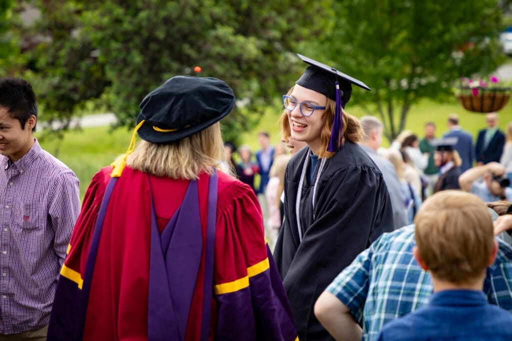 Asbury University graduate smiles with her professor at Commencement.