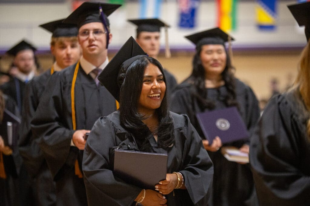 Asbury University graduates smile and hold diplomas at Commencement