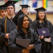 Asbury University graduates smile and hold diplomas at Commencement