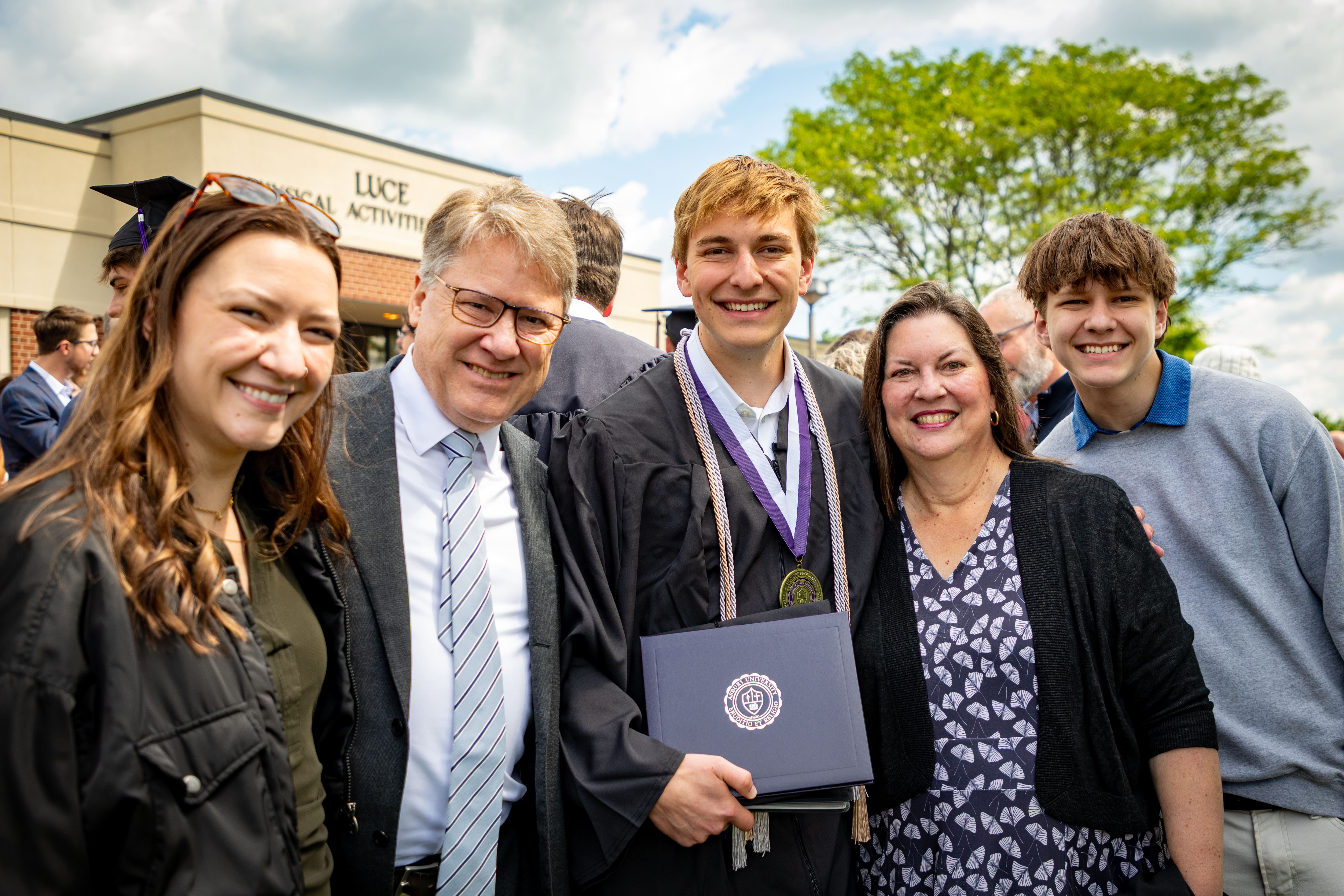 Asbury University graduate smiles with his family at Commencement.