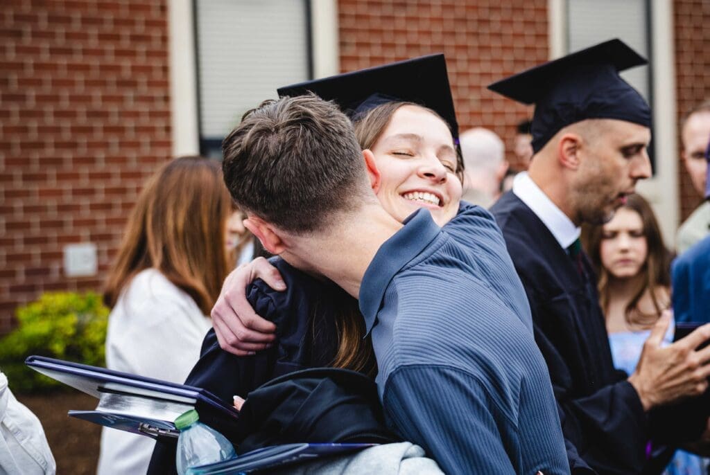Asbury student hugging another person in excitement post commencement.
