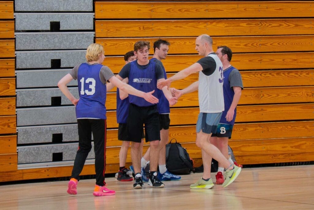 Asbury President giving high fives to co-ed intramurals basketball group of students.