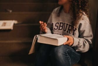 Asbury student with Bible open sitting and communicating with her hands.