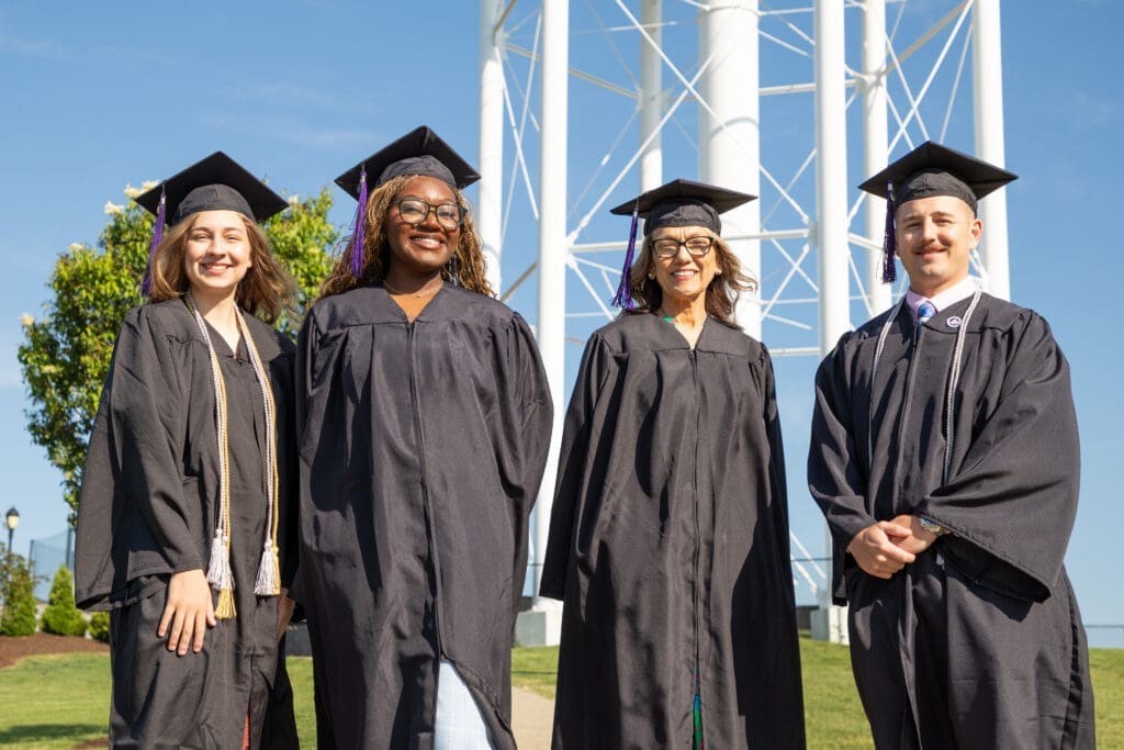 Asbury Online graduates smile in their caps and gowns.