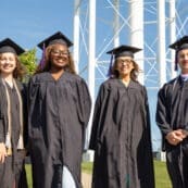 Asbury Online graduates smile in their caps and gowns.