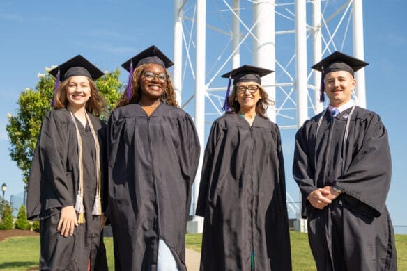Asbury Online graduates smile in their caps and gowns.