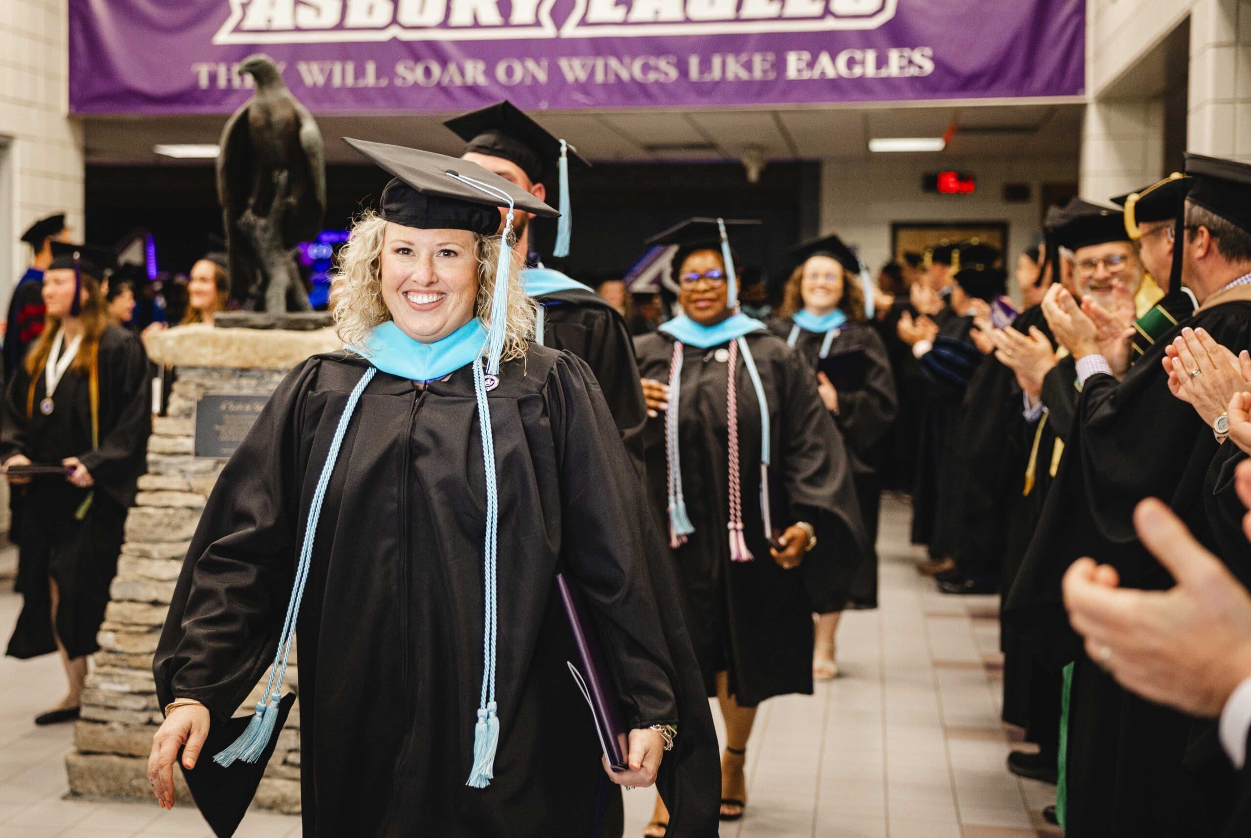 Group of Education graduates walking commencement at Asbury.
