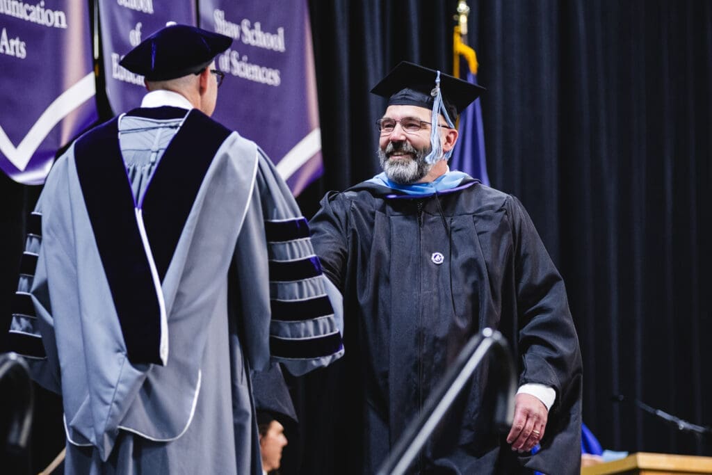 Asbury education online student graduating and receiving their diploma from Asbury President Kevin Brown.