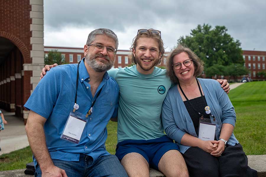 Group of three sitting outside on Asbury's campus during Reunion.