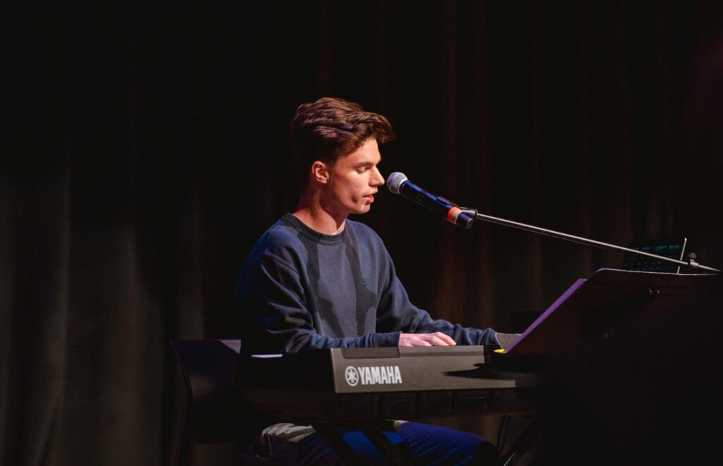 Asbury University and Trellis Partnership dramatic lighting of a male student playing piano at a concert.