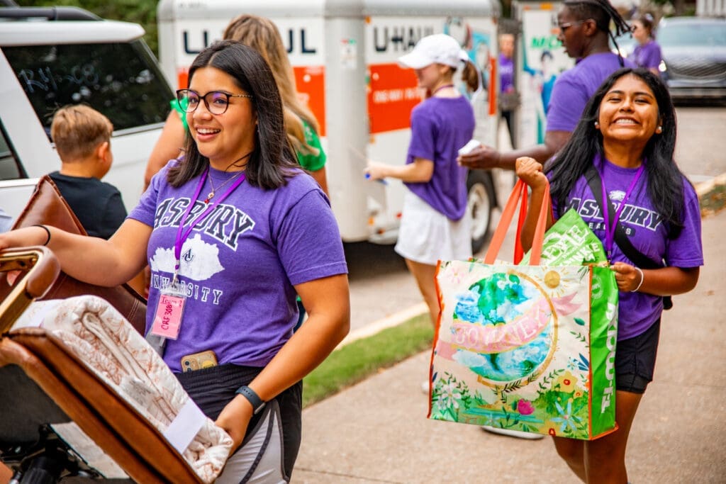 Asbury students smile and help new freshmen move into the residence hall.