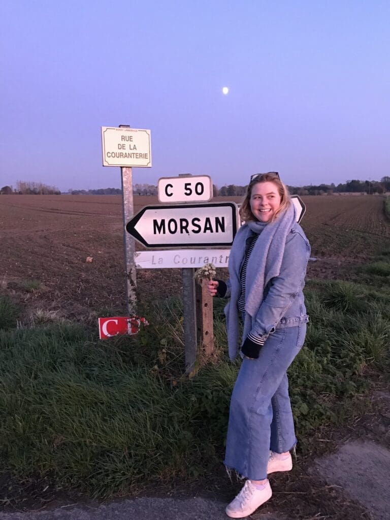 Student standing beside a road sign