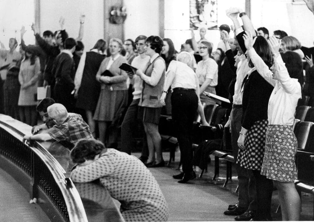 Students singing and praying in Hughes Auditorium