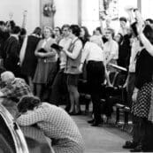 Students singing and praying in Hughes Auditorium