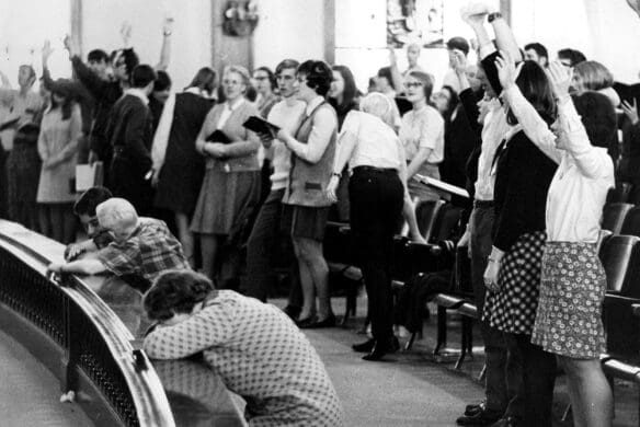 Students singing and praying in Hughes Auditorium