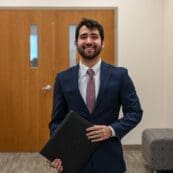 Student wearing a suit and holding a folder