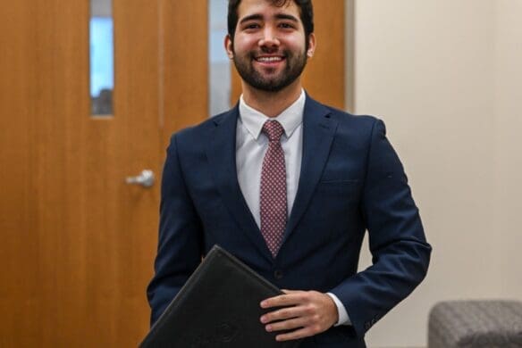 Student wearing a suit and holding a folder