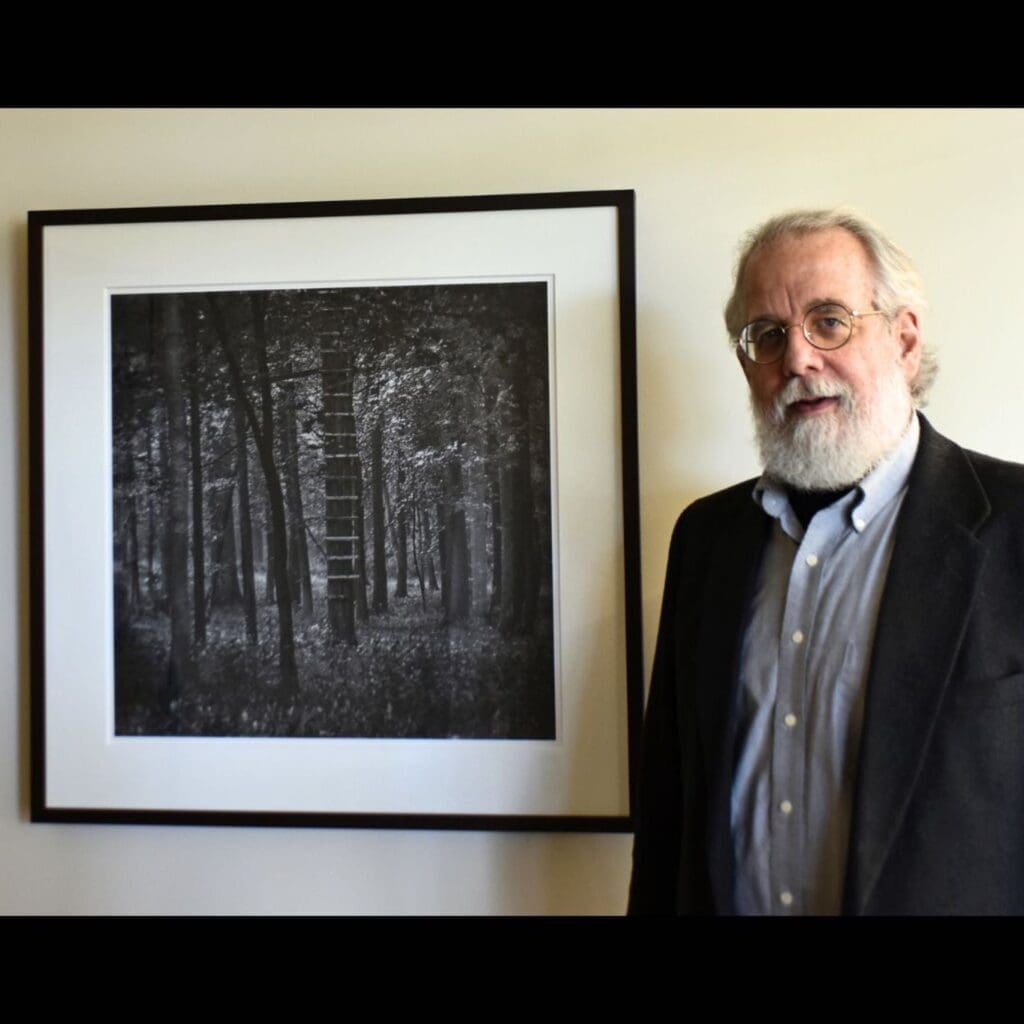 Glenn Howell standing next to an artwork hanging on a wall