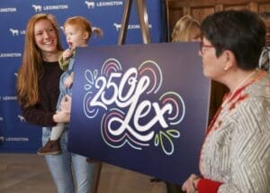 People unveiling a 250 Lex graphic design