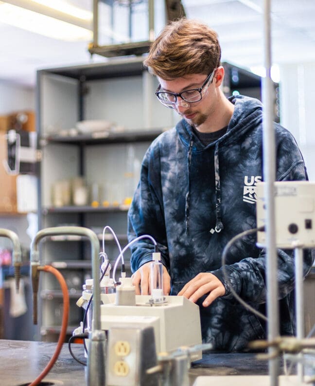 Male student uses chemistry equipment in a chemistry lab