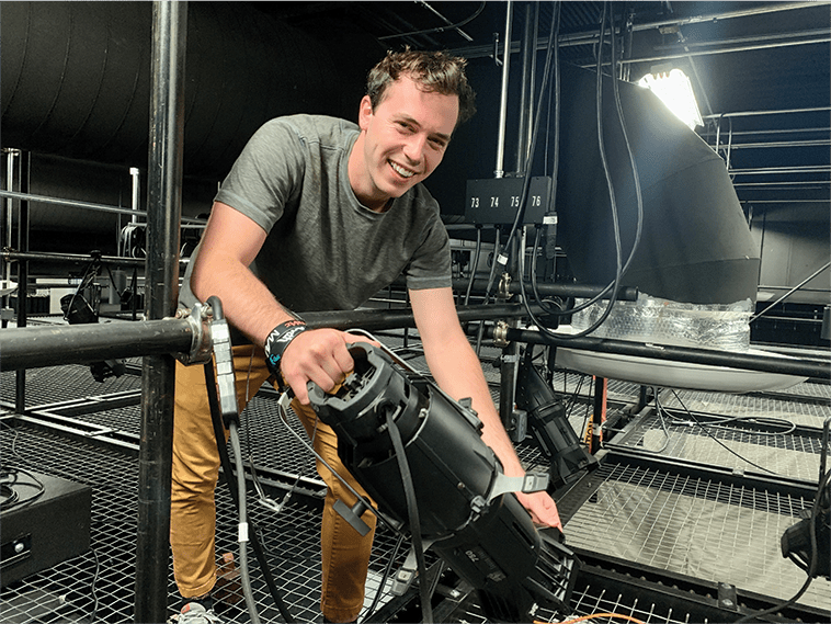Asbury University theatre student hanging lights in the grid,
