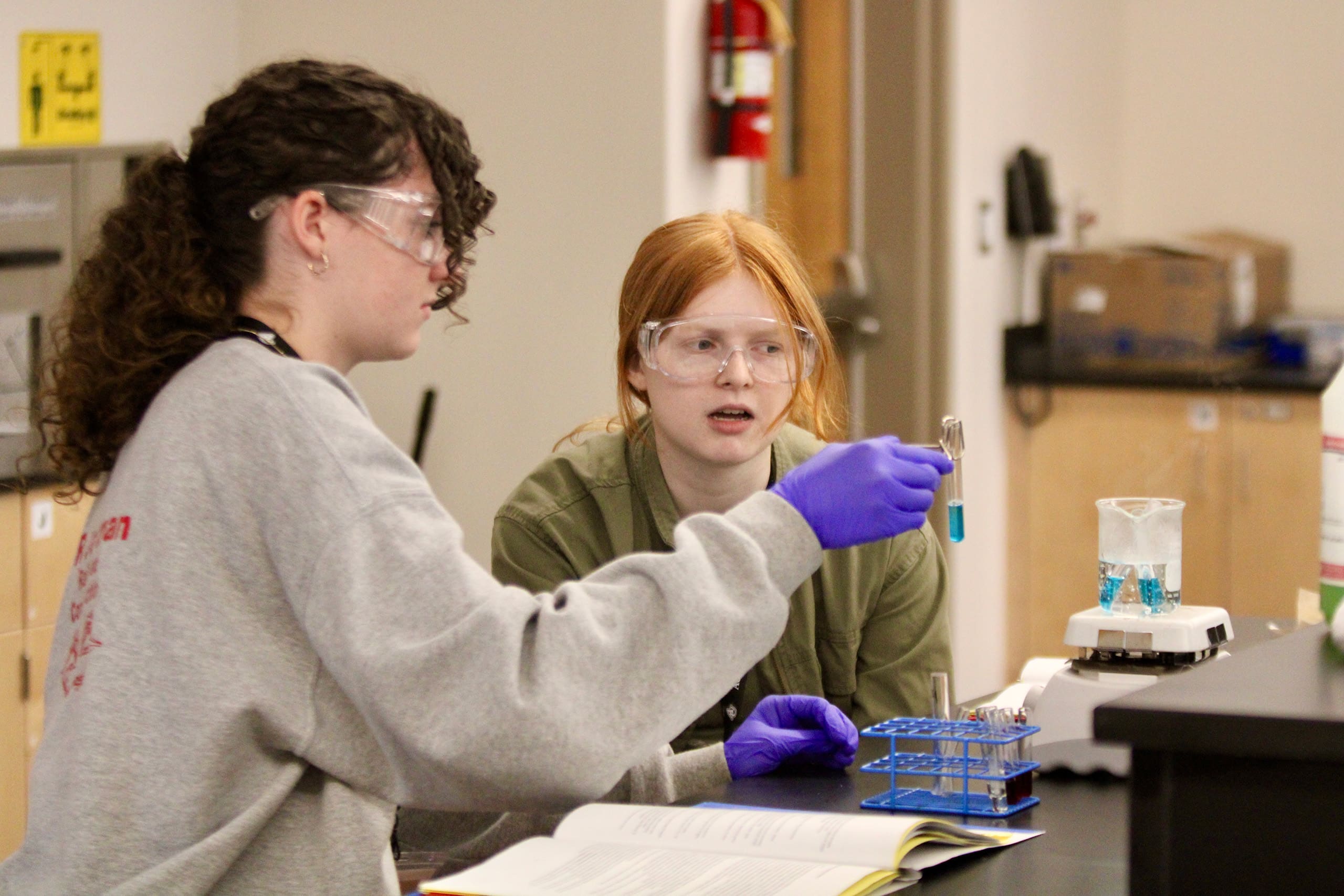 two students working with beaker in chemistry lab