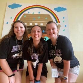 Three Asbury education students smile in a clasroom