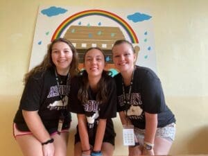 Three Asbury education students smile in a clasroom