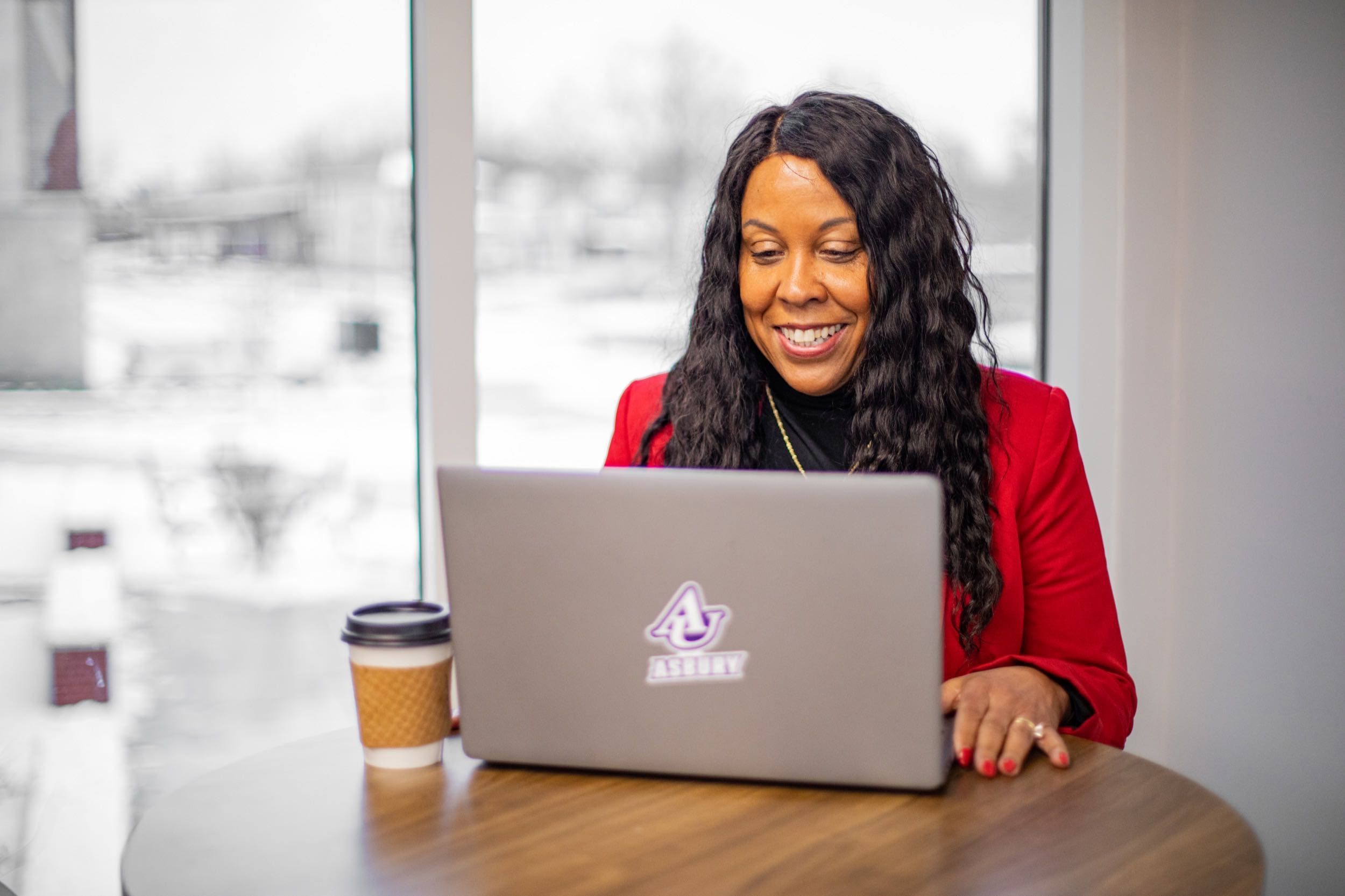 A woman who is an Asbury online student sits in front of a laptop at an office table