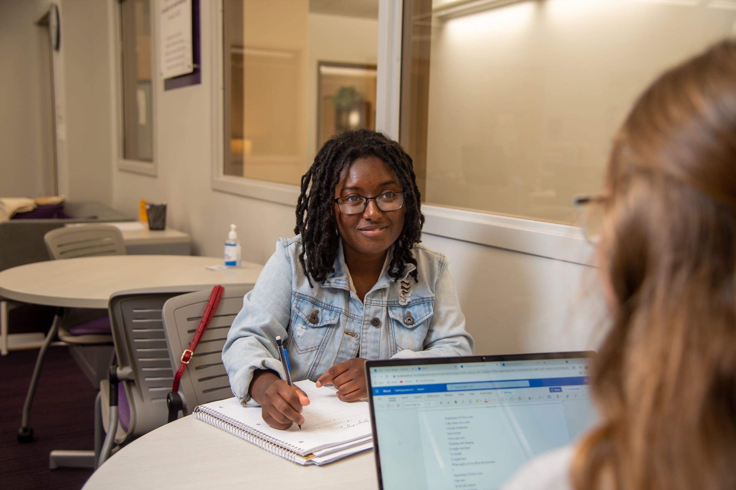 Female student sits across the table receiving academic support from a coach