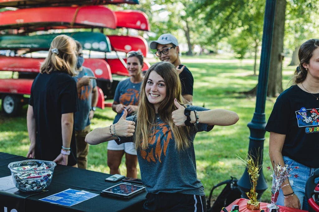 Asbury female student gives a thumbs up sign from an outdoor table 