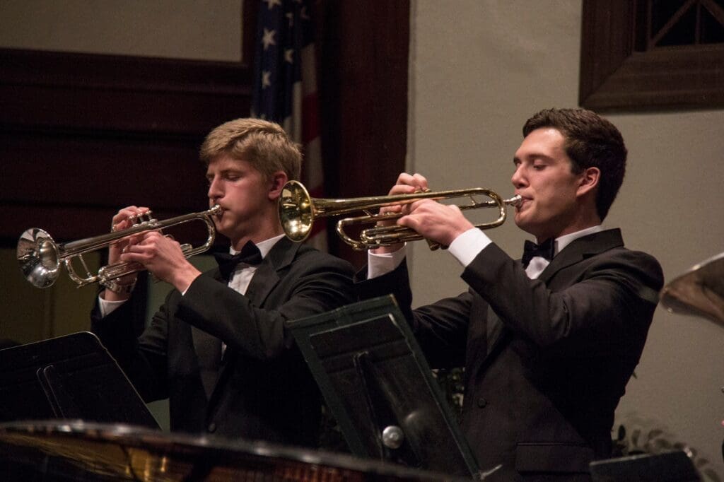 Two trumpet players performing in suits.