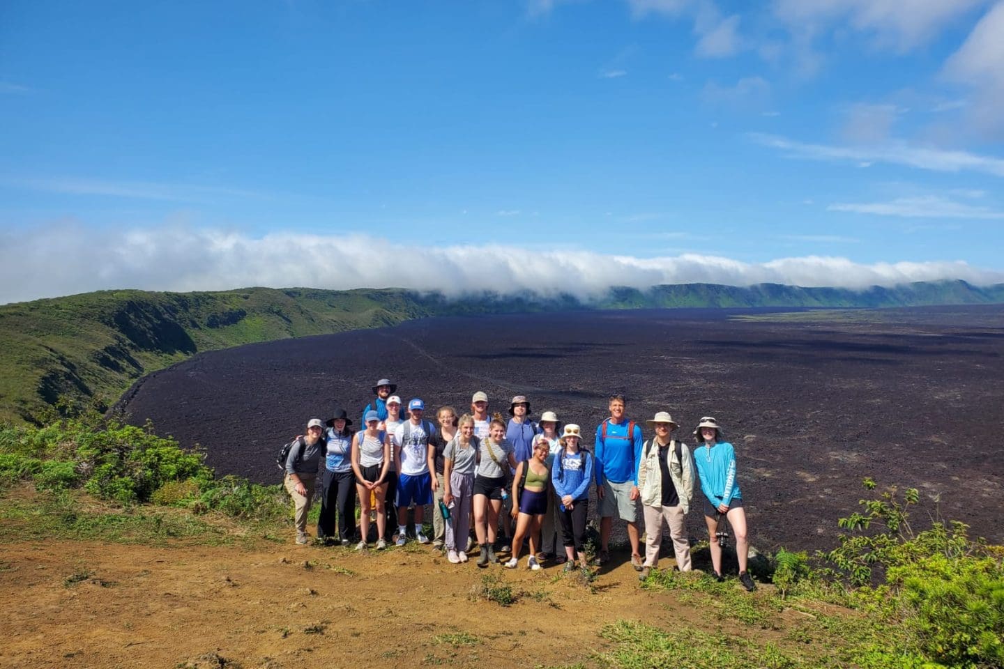 Group of Asbury students pose outdoors at the Galapagos Islands in a tropical setting