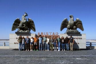 Students pose outside a monument of two alrge eagles