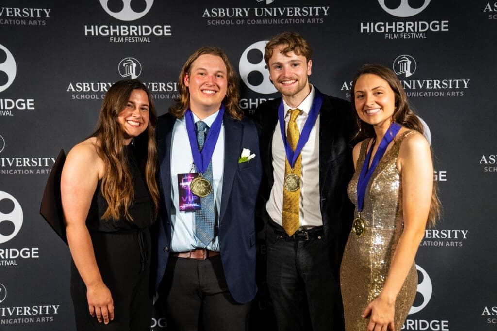 Four students with medals pose in front of a Highbridge film festival backdrop at the red carpet