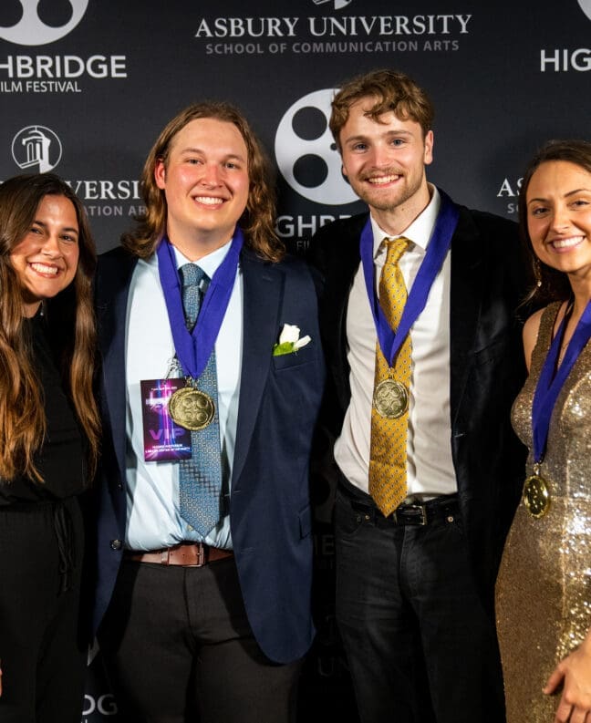 Four students with medals pose in front of a Highbridge film festival backdrop at the red carpet