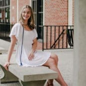 Picture of female Asbury student sitting outside in a white dress