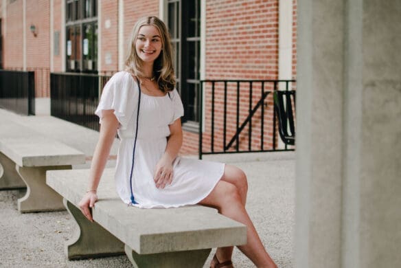 Picture of female Asbury student sitting outside in a white dress