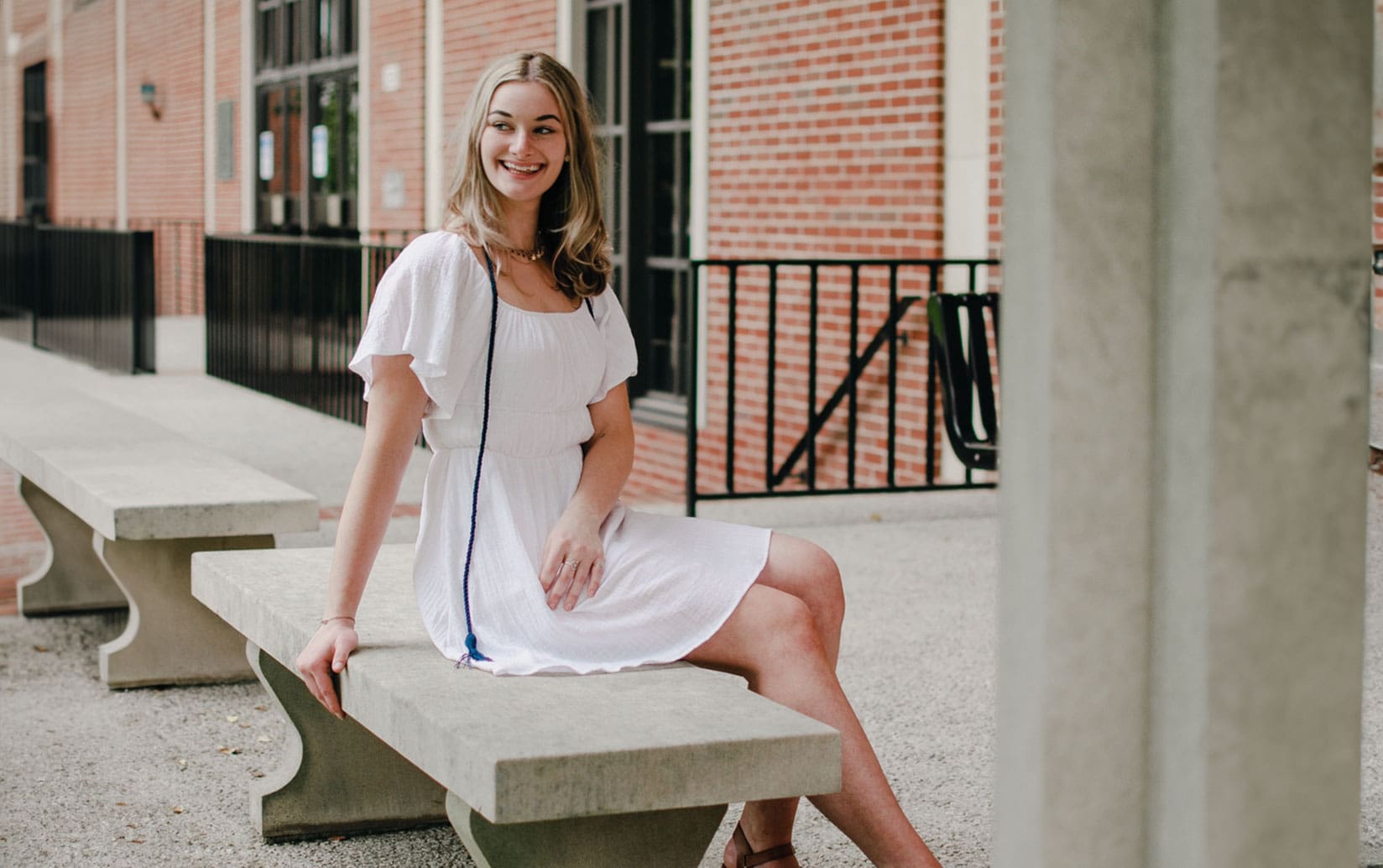 Picture of female Asbury student sitting outside in a white dress