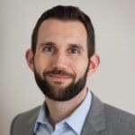 Headshot of smiling man with beard wearing a suit jacket