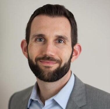 Headshot of smiling man with beard wearing a suit jacket