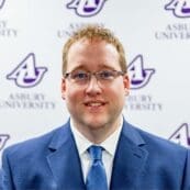Andy Miller stands in front of an Asbury University backdrop.
