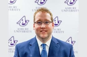 Andy Miller stands in front of an Asbury University backdrop.