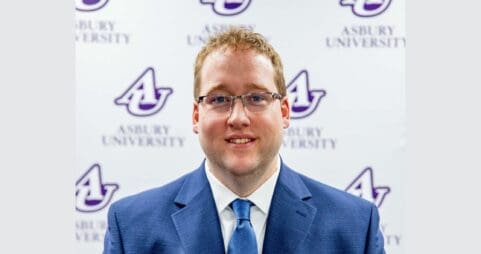 Andy Miller stands in front of an Asbury University backdrop.