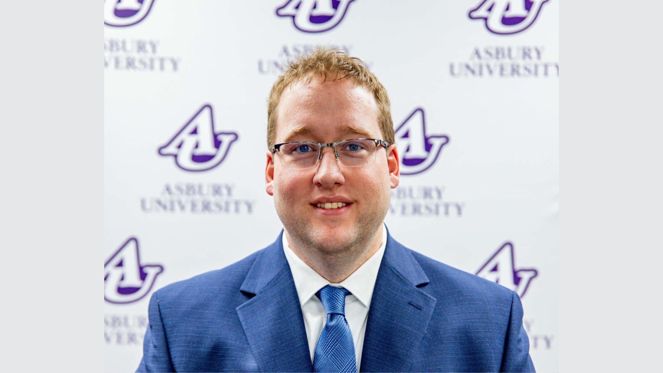 Andy Miller stands in front of an Asbury University backdrop.