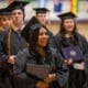 Asbury University graduates smile and hold diplomas at Commencement